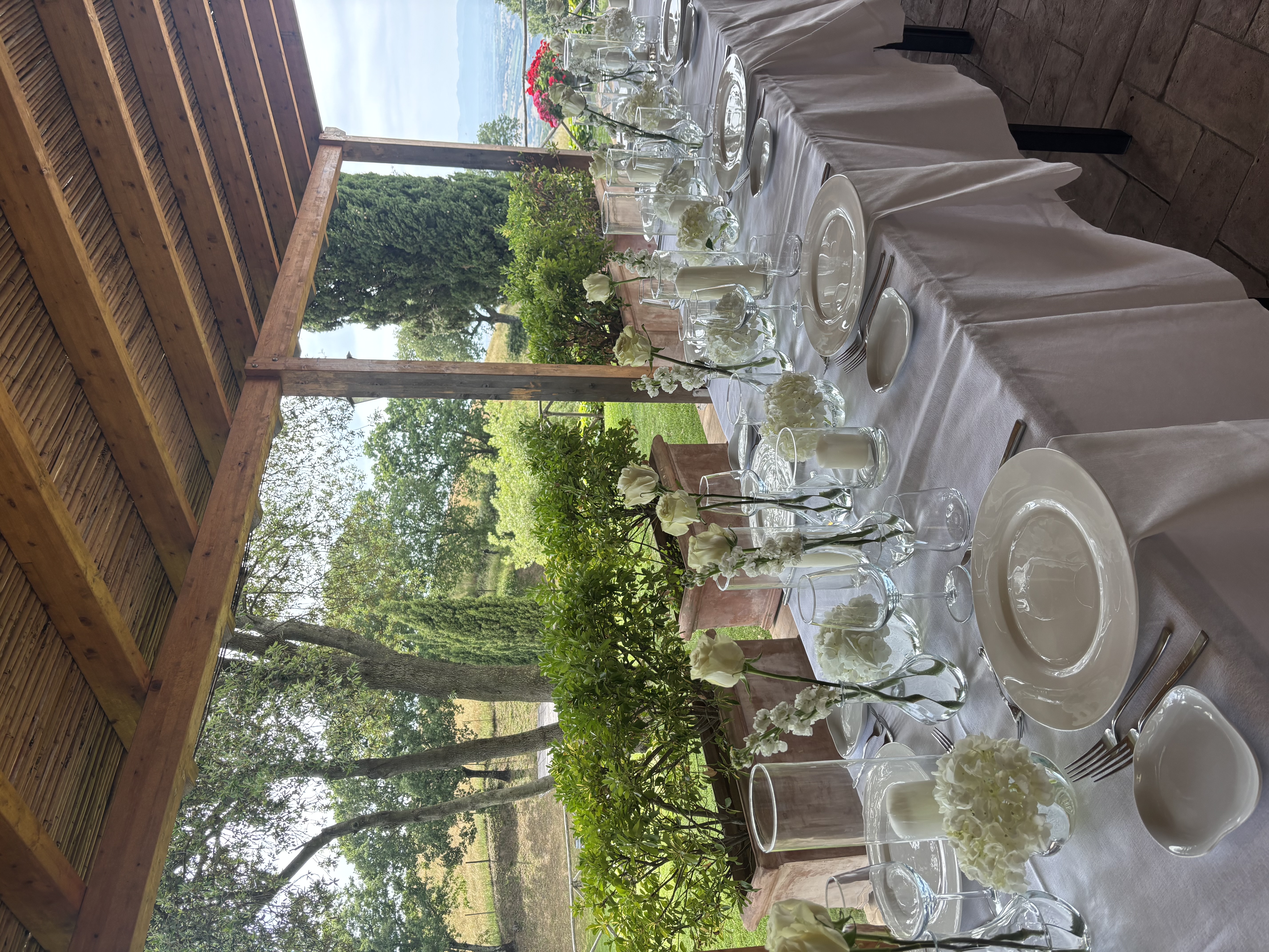 Tavola nuziale con rose e ortensie bianche e vista sulle colline